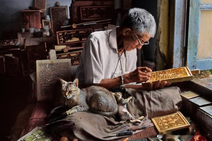 2001年，印度，在小猫陪伴下雕刻印刷版的木雕师 
