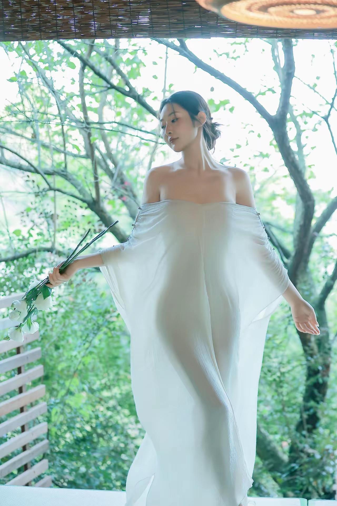 在自然中，一袭白裙，手持鲜花，静谧而美好。