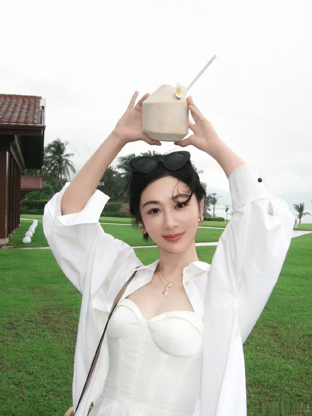 杨紫草帽白衬衫造型杨紫手拿椰子plog杨紫手拿椰子plog，蓝天白云和棕榈树，真