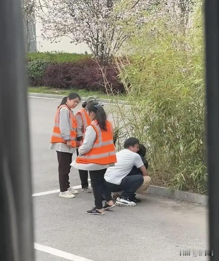 路边一男一女，两个人在争夺一部手机，女的蹲地上，死死护住手机，求助旁边扫地大妈，