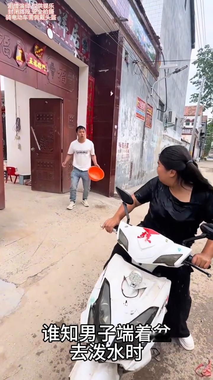 女子骑车正走时被男子泼了一身水，这一幕真的太无奈了。
女子骑着电动车正在路上走，