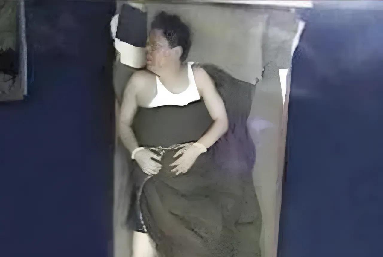 2010年，文强戴着手铐，身穿一件白色的背心，躺在一张床上休息，这是当时监控拍下