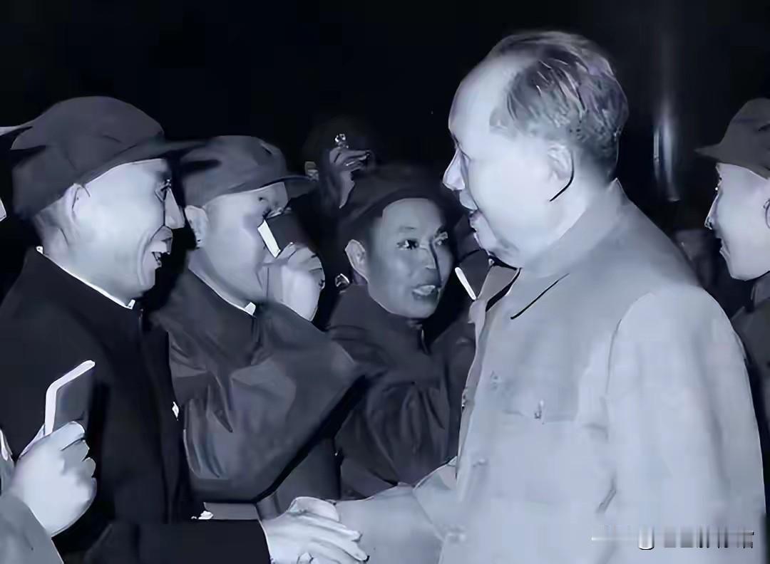 珍贵黑白历史影像里，毛主席亲切伸出手与基层同志紧紧相握，身旁众人面露欣喜、满怀热