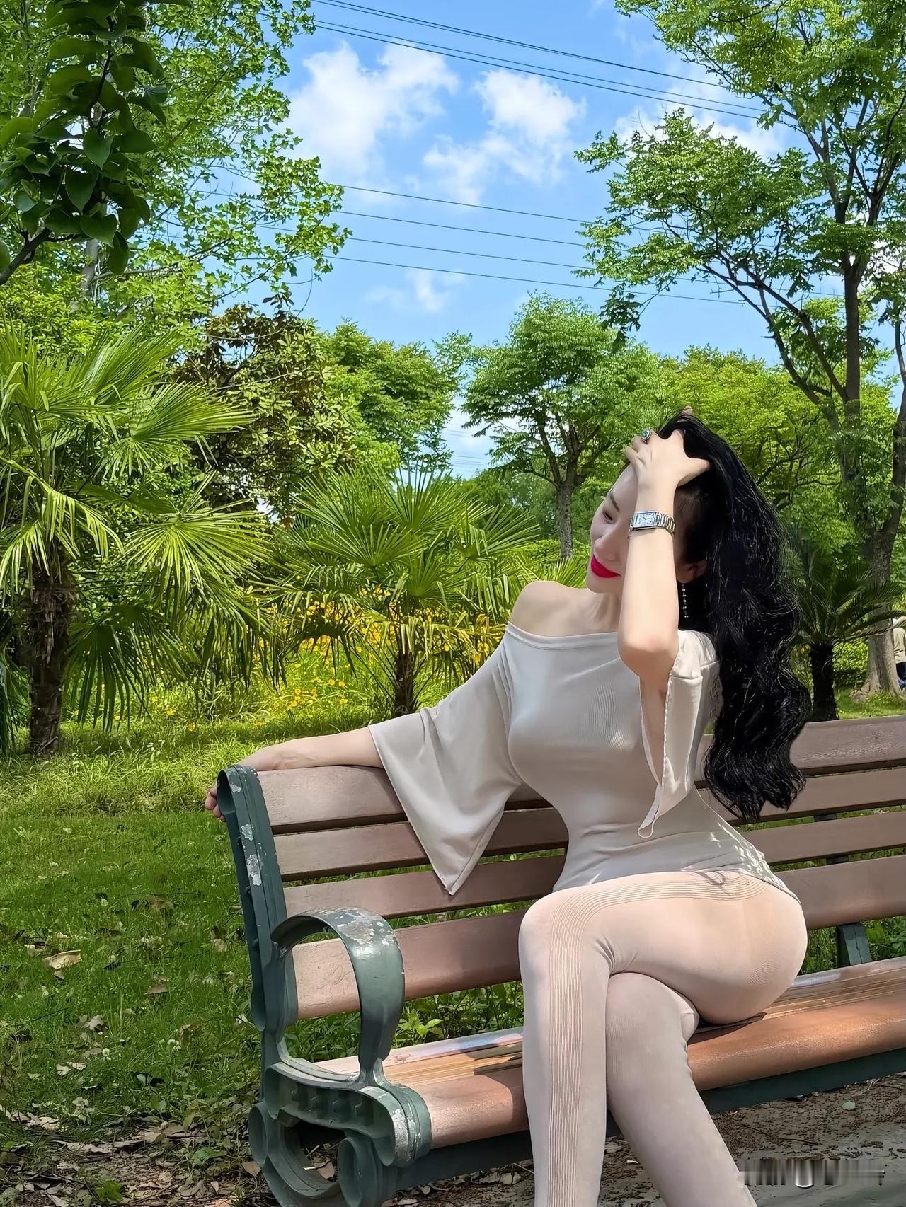阳光明媚的公园里，优雅的女士坐在长椅上，享受着宁静的时光。