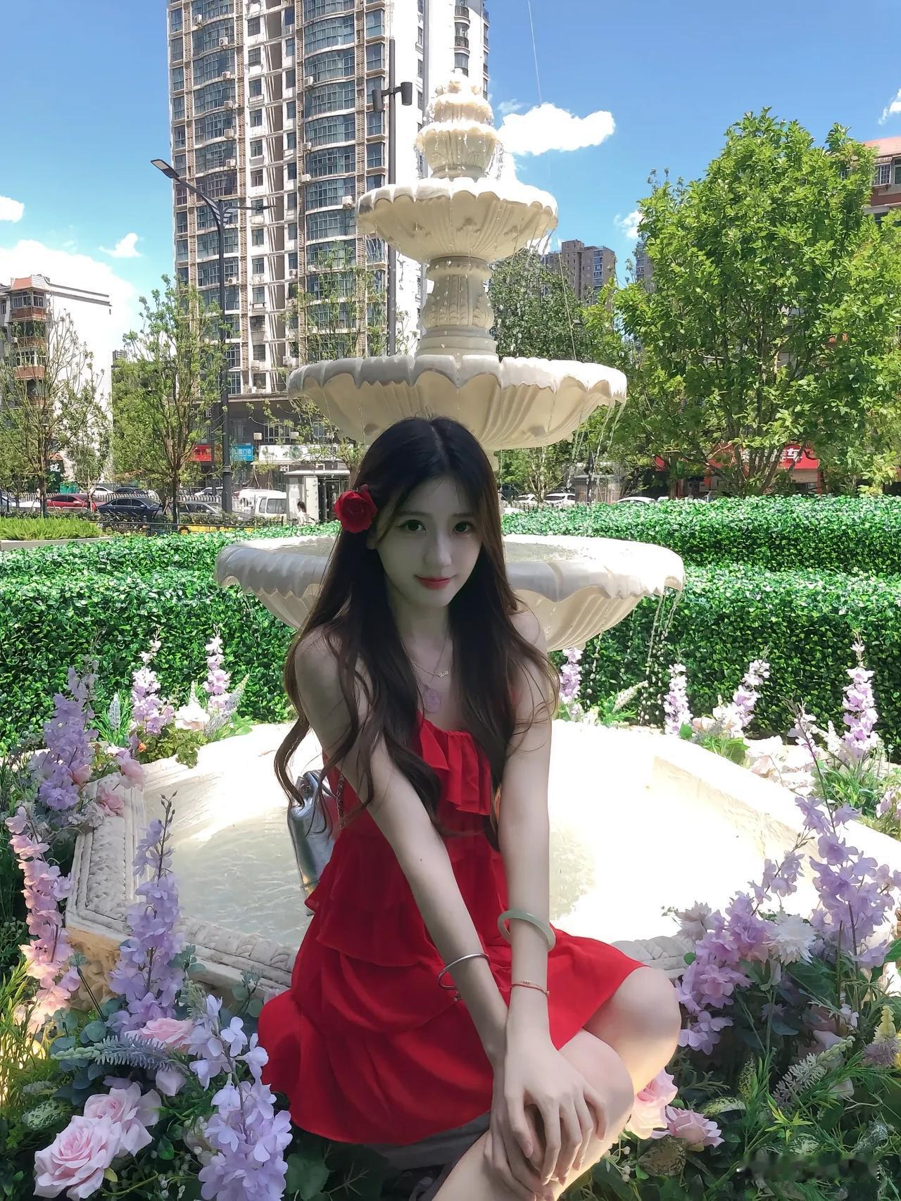 红衣美人倚喷泉，花影摇曳映芳颜。