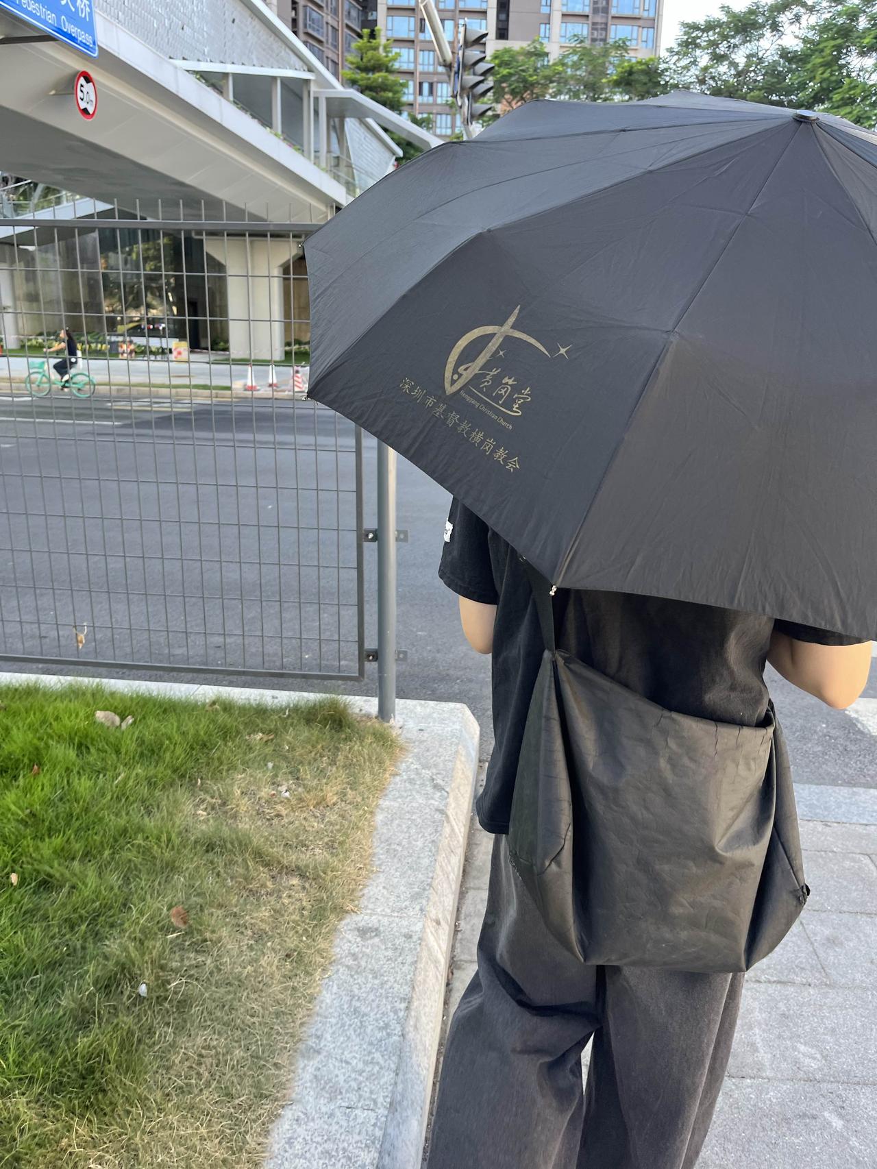 一个人打着伞在等红灯，这伞是基督教教堂发的，其实这个是什么价，我也不太了解，但是
