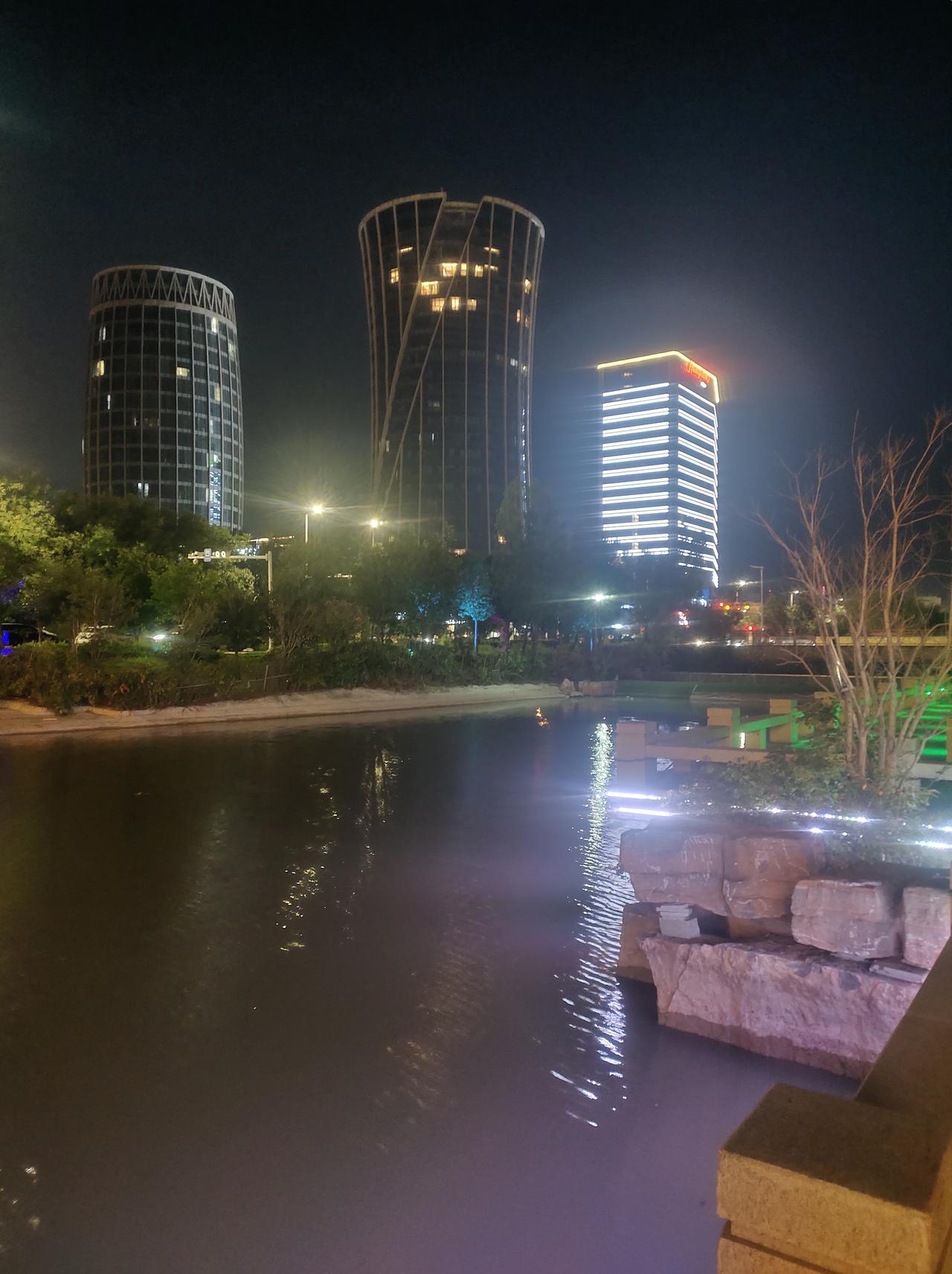 夜晚河畔，灯火阑珊，现代建筑倒映在静谧的水面上，景色如画，令人沉醉。🌃.🌉