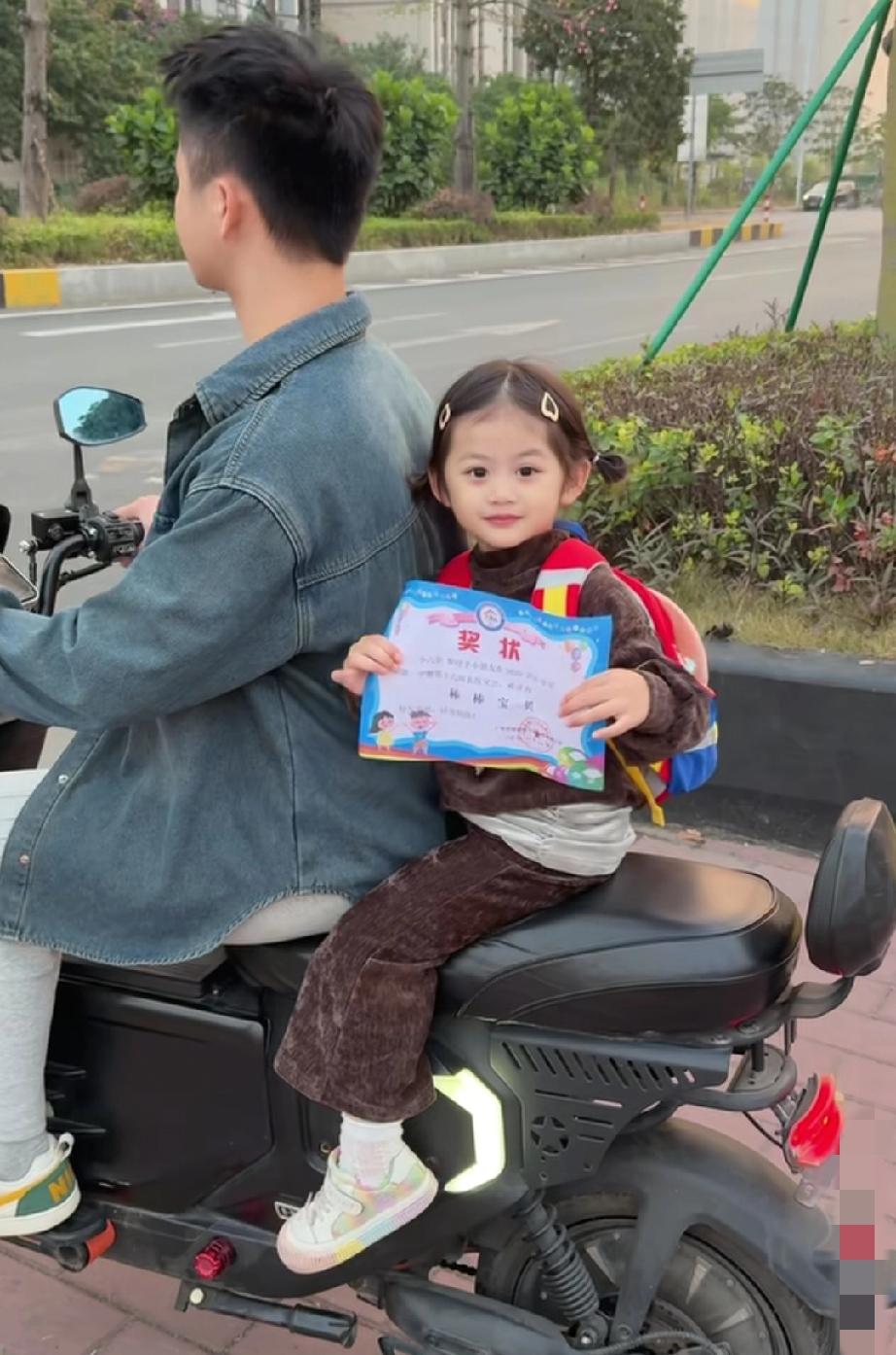 这小女孩的快乐都要溢出屏幕了！
爸爸接放学遇红灯停车，小丫头立马举着刚到手的奖状