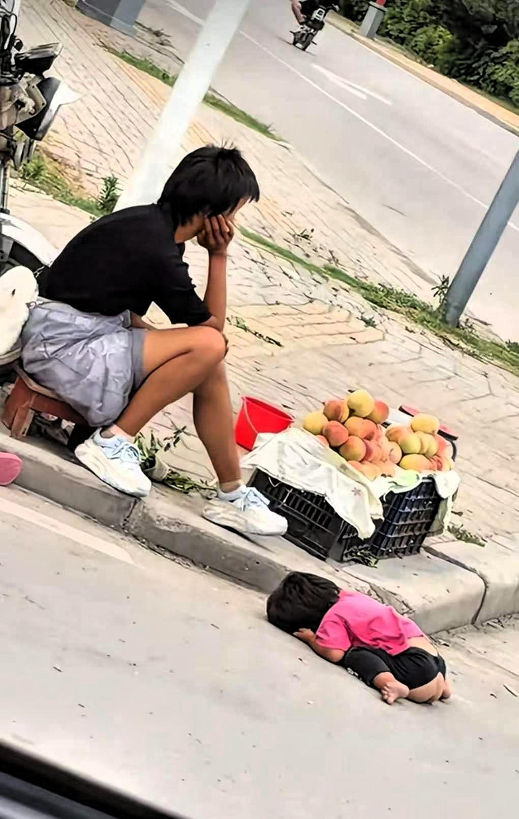 这是谁的女儿，谁的妻子，又是谁的孩子？烈日炎炎下，一名女子坐在街头，面前摆着一筐