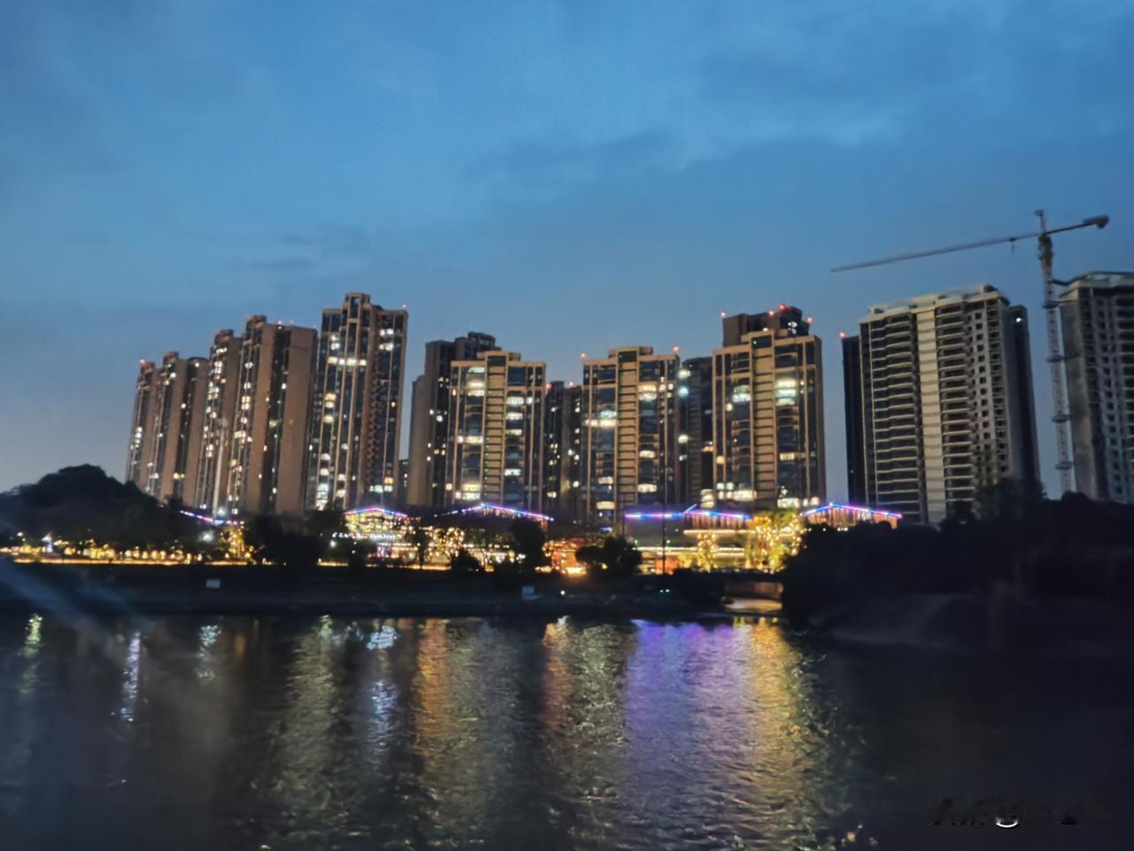 晚风吹拂，水面上摇曳着碎金般的灯光，对岸的楼群闪烁着星星点点的光亮。

右侧还有