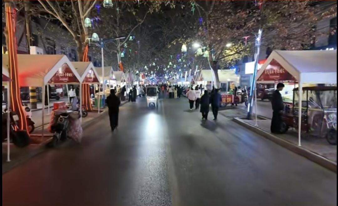 分享一下你随手拍下的照片冬夜的小吃一条街，灯火阑珊处，孩子在妈妈的怀抱里享受着幸