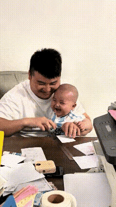 刷到这段视频我跟着笑了半天，心里软乎乎的。
爸爸拿尺子压住纸一撕，怀里的小宝贝立