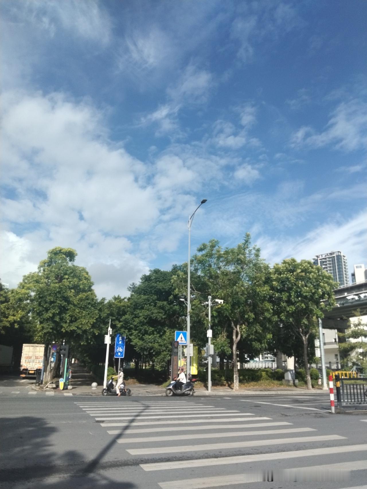 在路上随手拍下街头的风景，澄澈的蓝天缀满朵朵白云，微风缓缓吹散往日的闷热。马路边
