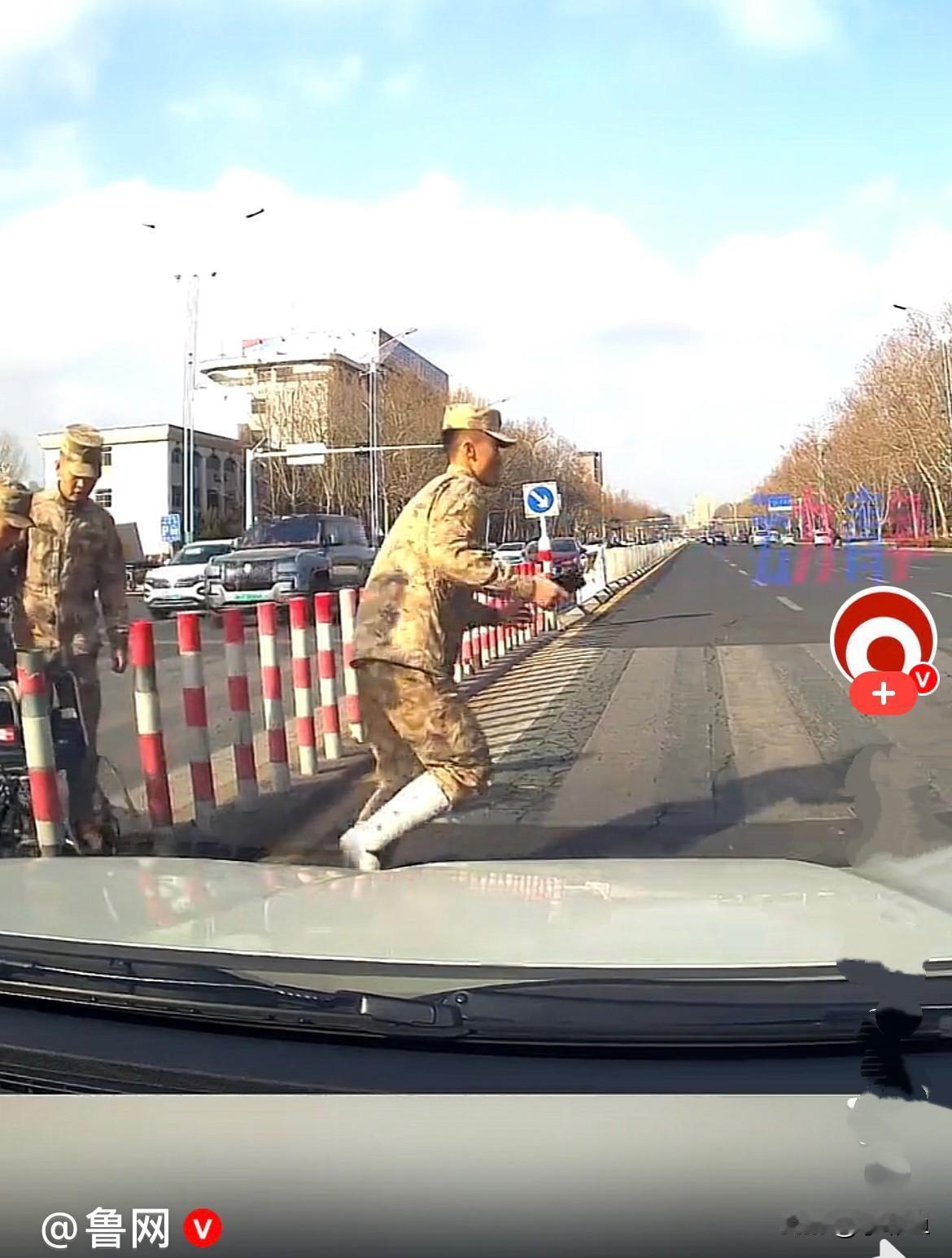 大年初八，山东潍坊一马路上，一位兵哥哥腿部受伤了打着石膏坐在轮椅上，一位战士推着