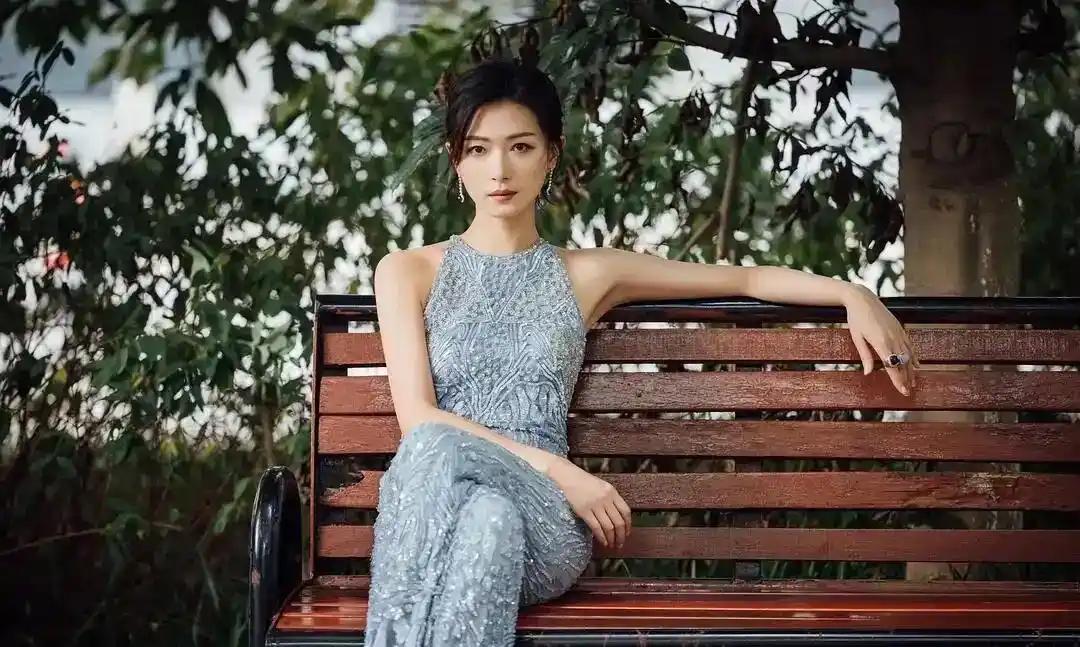 一个穿裙子的女人坐在长椅上。真的是太漂亮了运气和努力那个更重要 你喜欢以前的秋收
