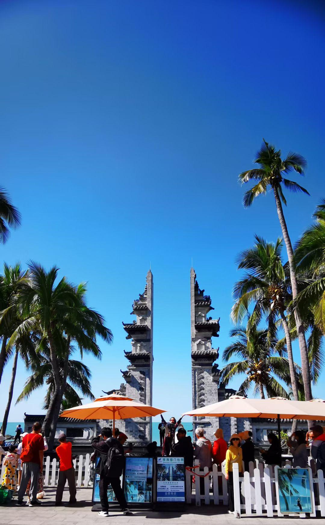 椰风把蓝天吹成透亮的绸，古牌坊立在日光里像本翻开的史卷，人群在橙伞下聚成活泼的注