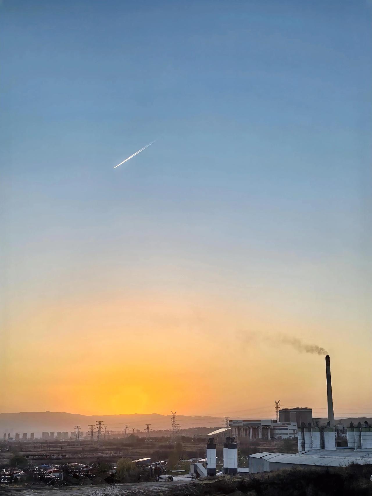 这一张照片极有特色，落日、孤烟，还有飞机拉出来的喷气……