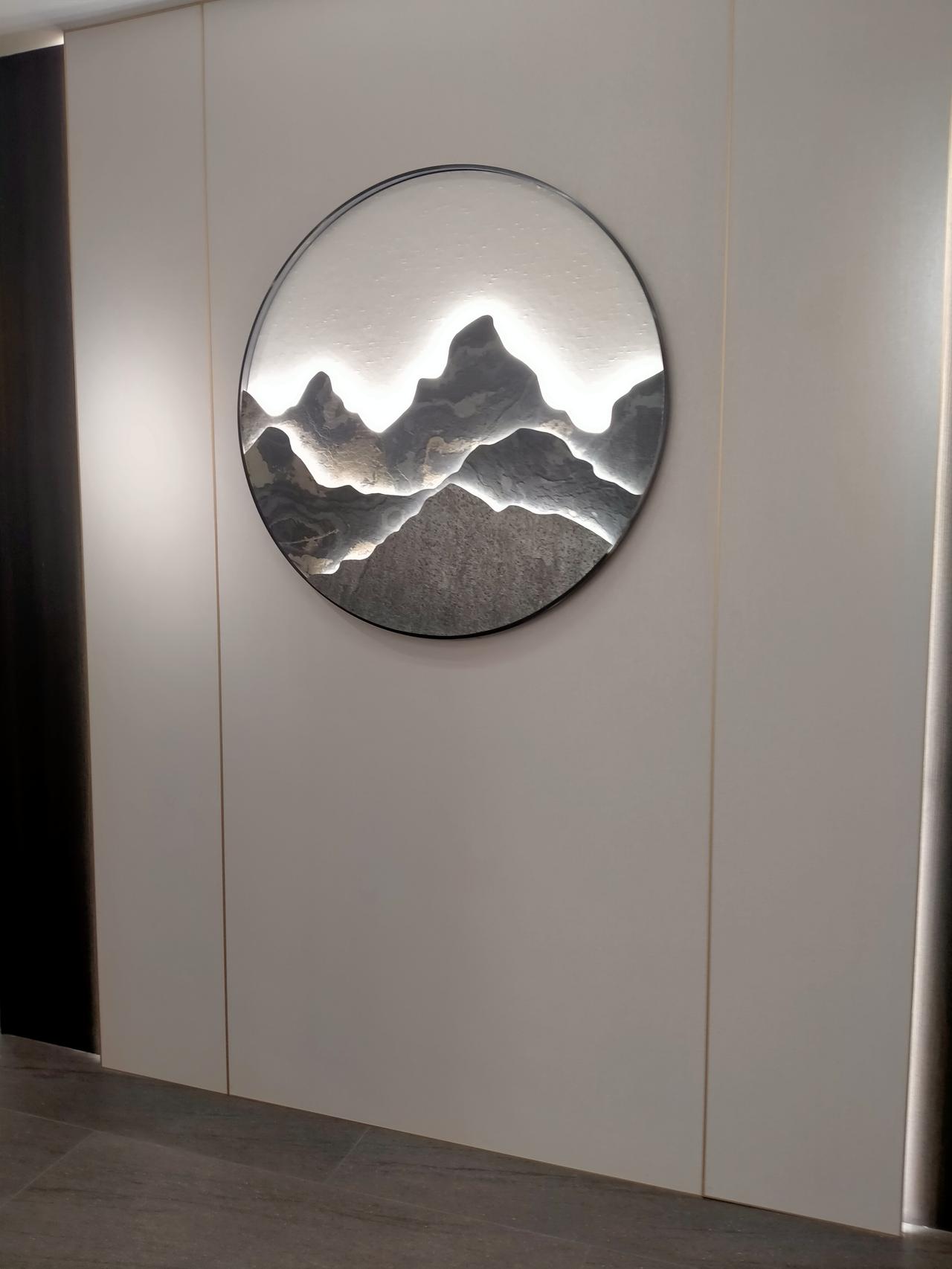 圆形的画框圈住层叠山峦，内嵌的灯光勾勒出峰峦的起伏轮廓，明暗交错间，传统山水的诗