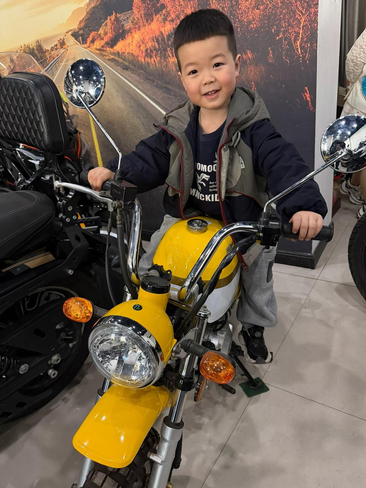 小男孩骑黄色摩托车，开心笑。