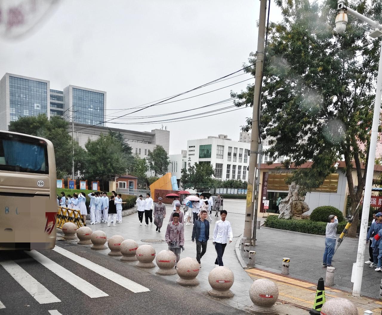 昨天下午一点半左右经过即墨德馨小学，看到学生们穿着演出服在门口乘坐大巴车，下雨天