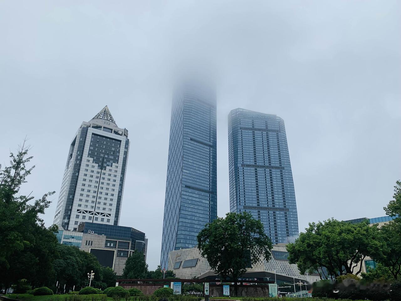 一场细雨，高楼半隐云雾，一边是都市摩天的巍峨，一边是街巷寻常烟火。
（手机摄）