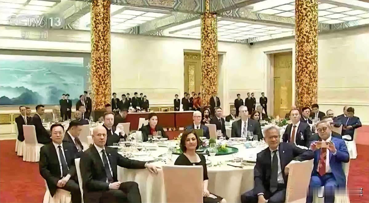 左边坐着库克，右边挨着马斯克，对面是黄仁勋。周群飞坐在这张桌子的C位，凭的不是运