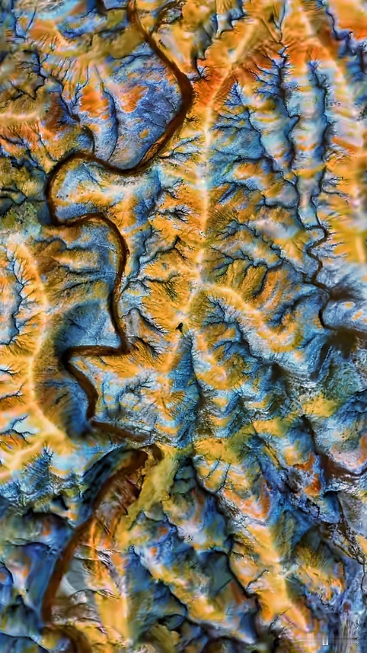 俯瞰大地，山河舒展成斑斓画卷。蜿蜒河道如褐色绸带，缠绕层叠山峦。沟壑纵横，橙黄与