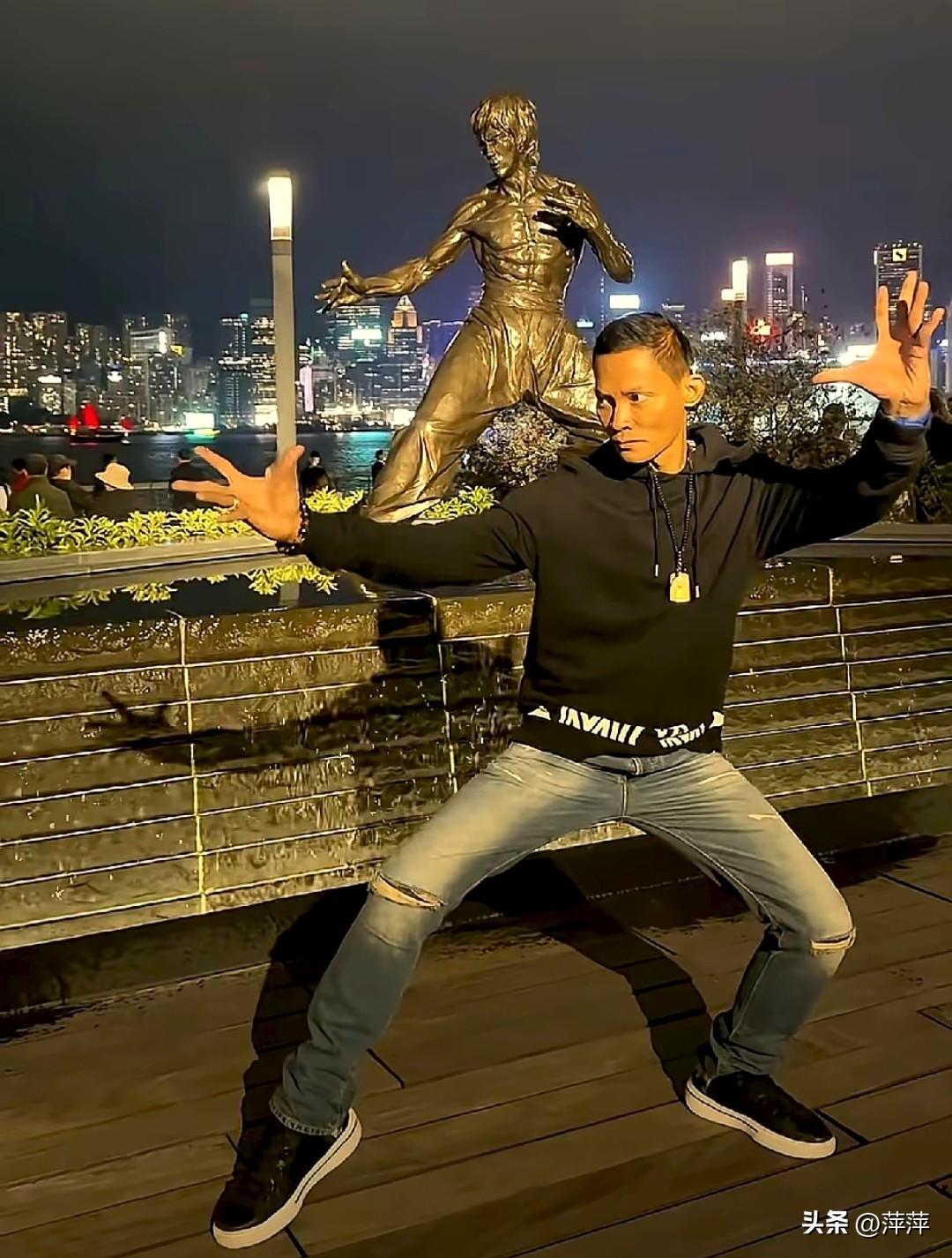 泰国动作明星托尼贾现身香港，在维多利亚港的李小龙铜像前摆出标志性武术姿势。他身着