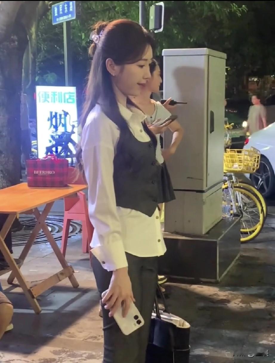 毛晓彤在街边拿着手机。