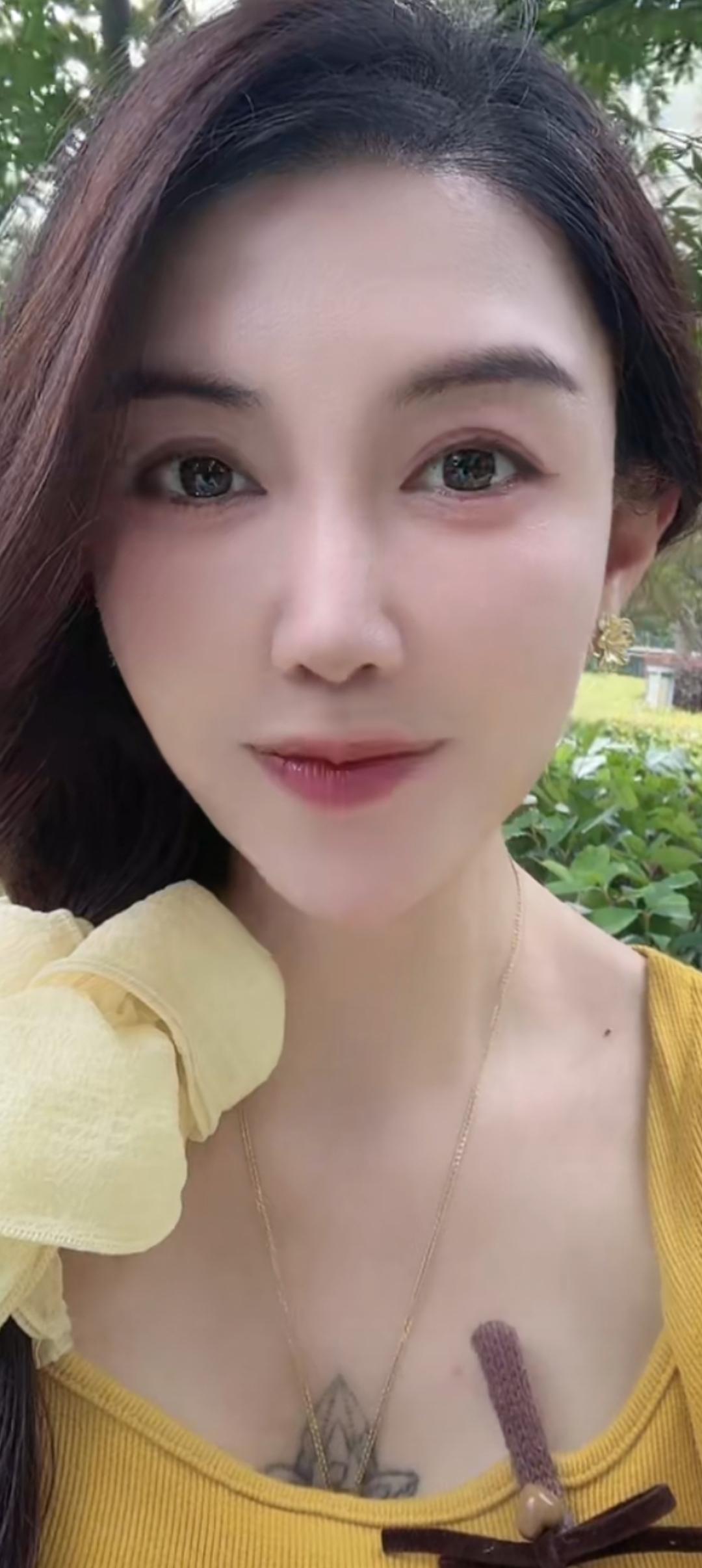 这个女孩穿着黄色上衣，戴着金色项链。