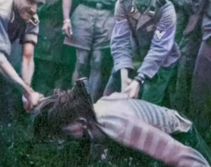 1942年一群党卫军士兵正在处决一名南斯拉夫女游击队员，只见一名党卫军死死拉着女