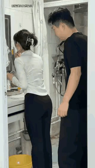 妻子正在化妆，丈夫从背后抱着妻子的腰，妻子瞬间翻脸，让丈夫走开，并推了丈夫一下。