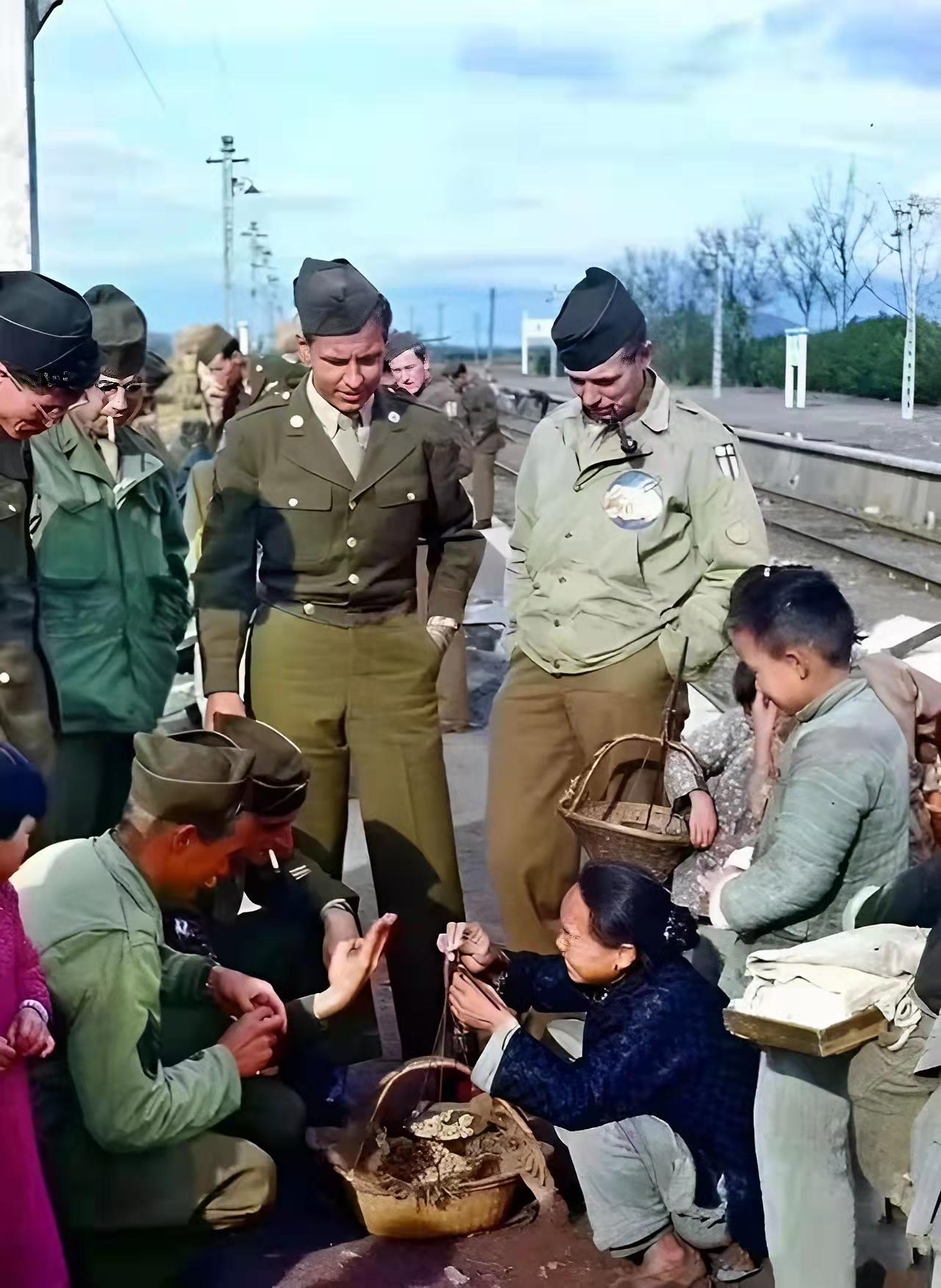美军大兵蹲在地上比比划划，只为跟中国大娘买口吃的。这是1945年杭州火车站的真实