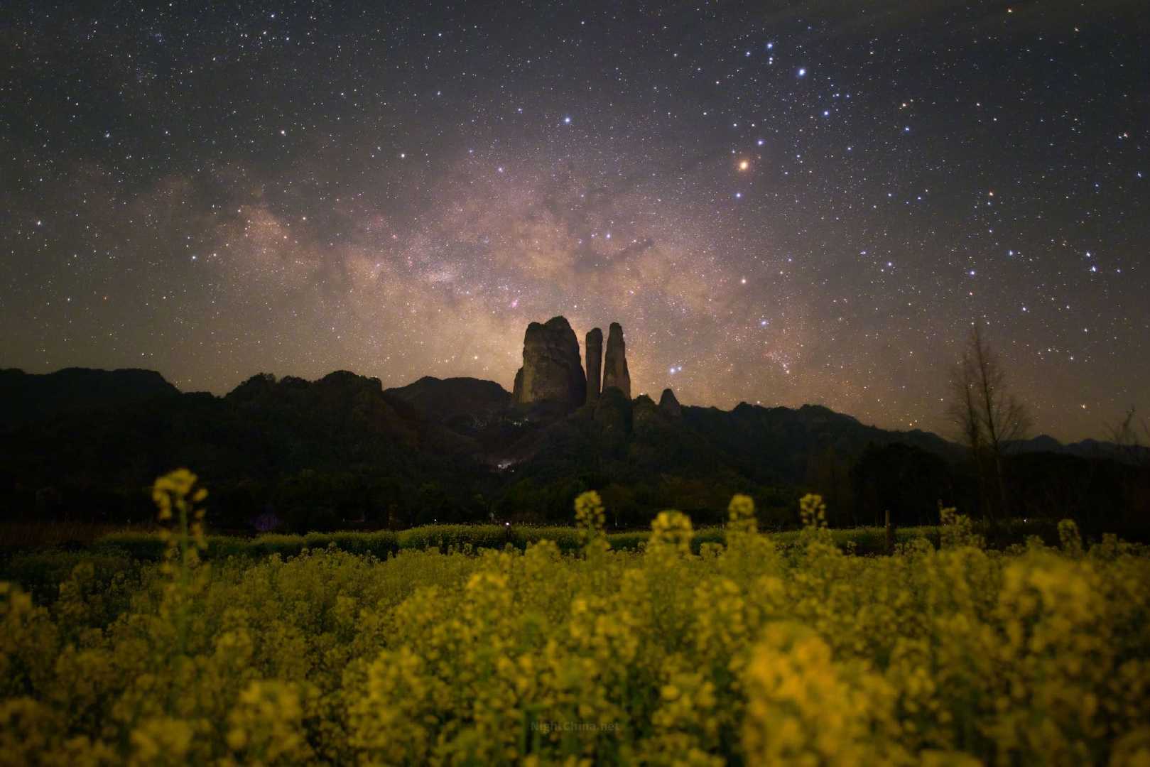 三月的油菜花将大地染成金黄，江郎山三峰静默于夜色之中，仿佛亘古的守望者。星河在山