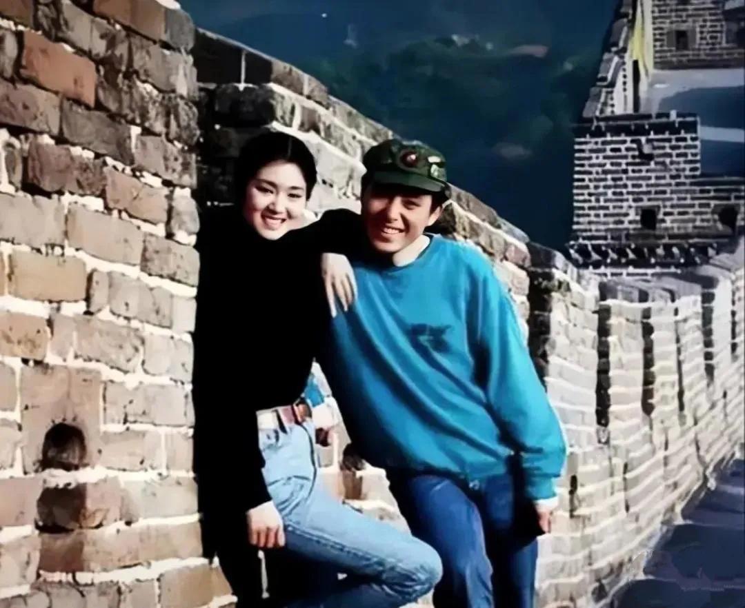 24岁的巩俐和张艺谋一起游玩长城，两人站在城墙边上，巩俐黑色紧身上衣搭配牛仔裤，
