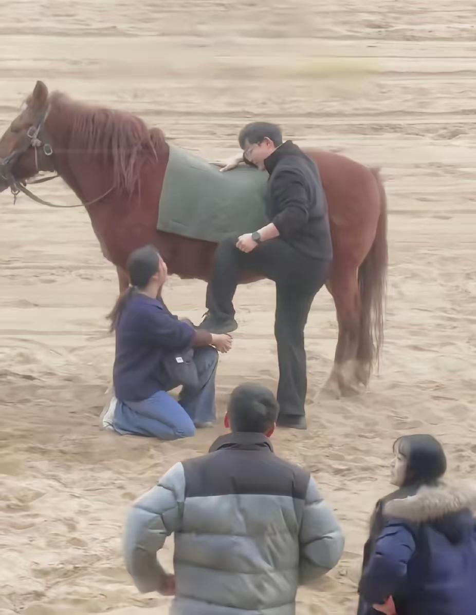 夫妻俩去景区玩，路过一片跑马场，妻子看到马就想试试，可怎么也爬不上去，急得直跺脚