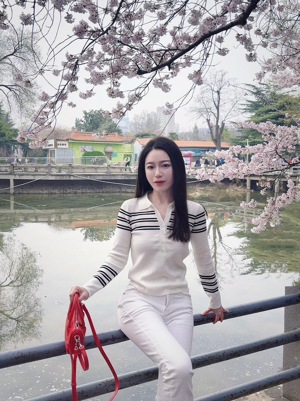 樱花树下，白衣少女倚栏杆，春意盎然。