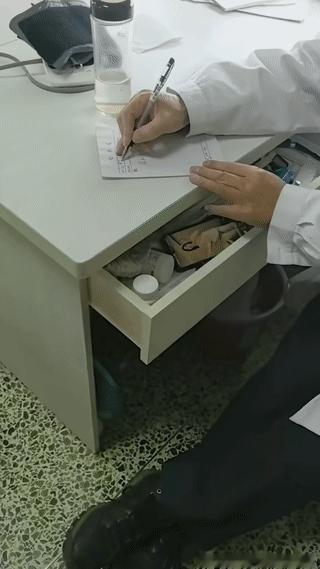 一名医生在给患者开处方的时候，在他办公桌下面的抽屉里竟然有手机正在播放美女跳舞视