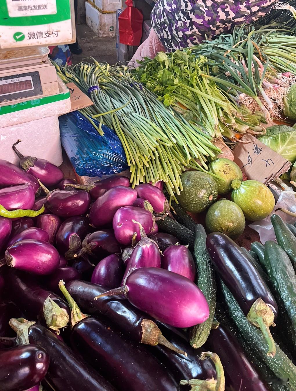逛菜市场总能把心里的浮躁都熨帖平了。

你看这摊子上，紫莹莹的圆茄子挤挤挨挨堆着