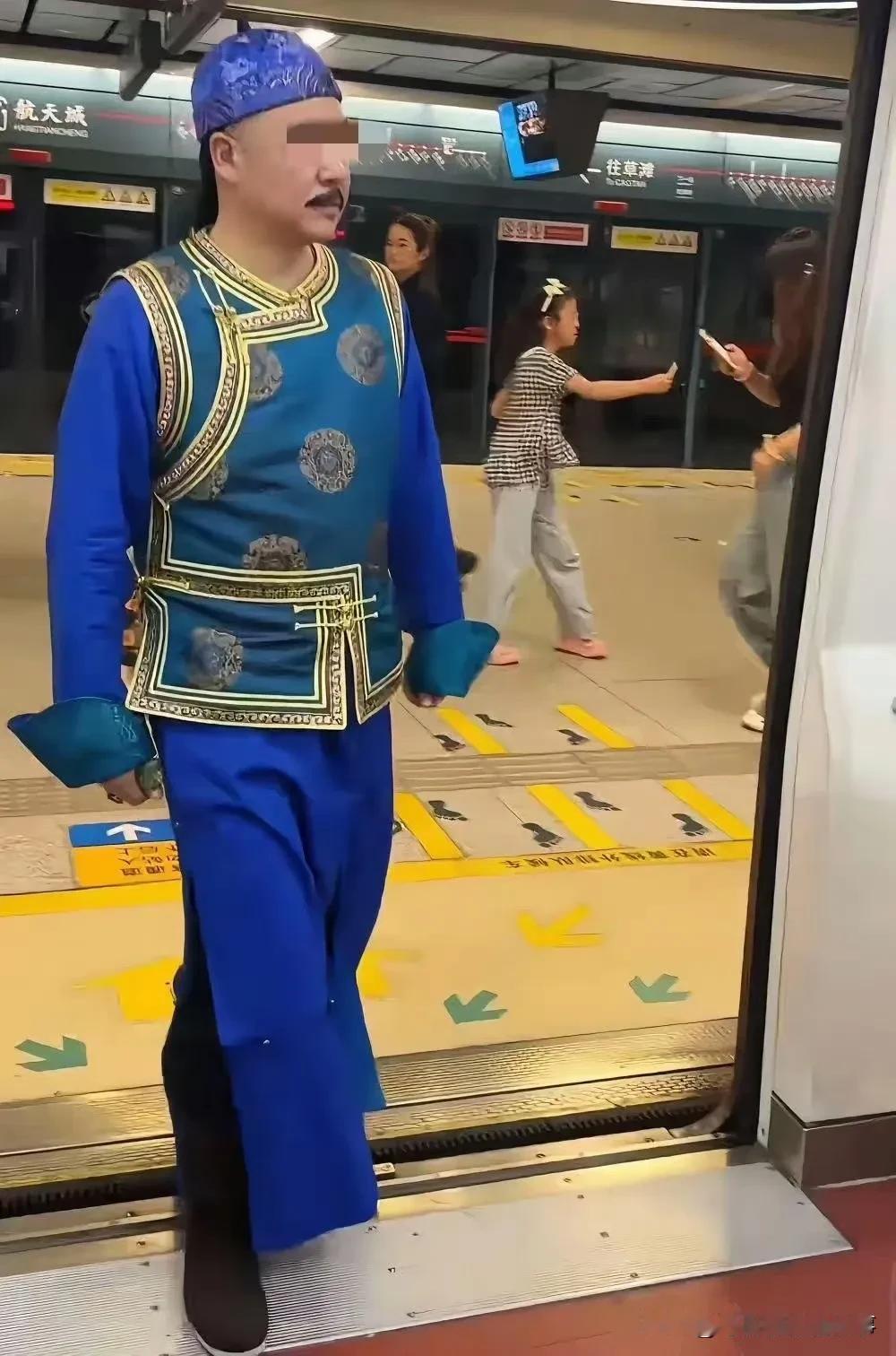 这位不知是汉族还是满族的中年人穿着满清贵胄服饰坐地铁，他面对满车厢诧异的目光是毫