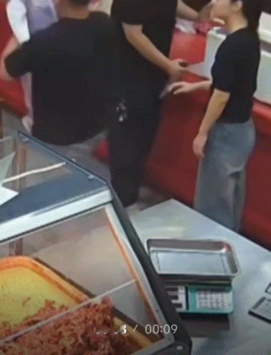 河南，一熟食店内的监控显示，一名男子手持刀具，刀刃向外的行走。期间男子将持刀手臂