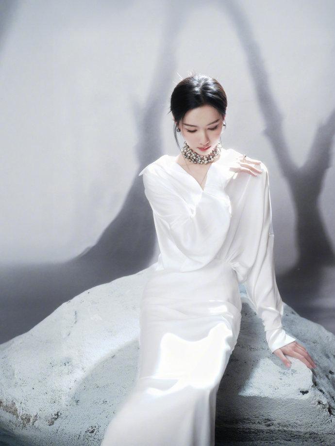 陈都灵一袭白色缎面长裙出镜，慵懒盘发搭配精致珠饰颈链，简约剪裁勾勒出曼妙身姿，清