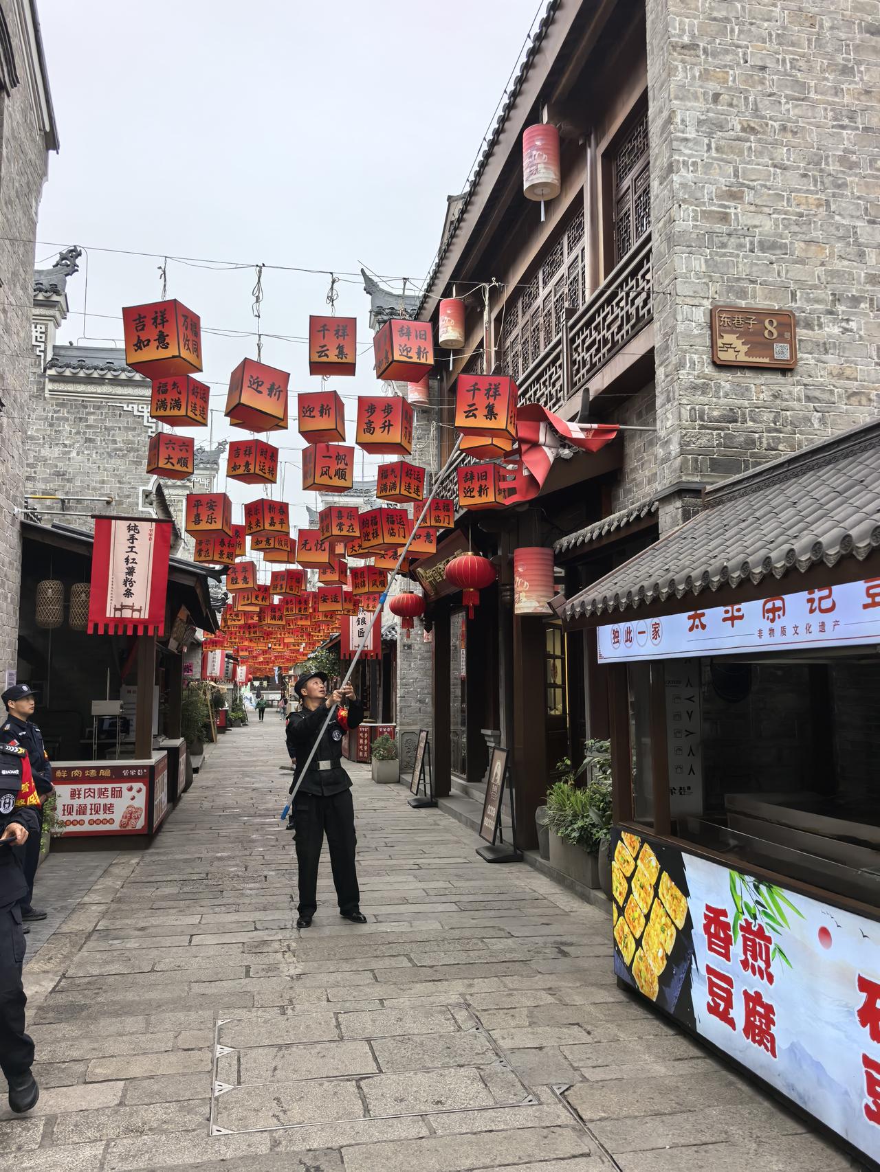 襄阳古城里物业的工作人员，可能每天早晨都进行巡视。店家的幌子被风卷堆了，工作人员