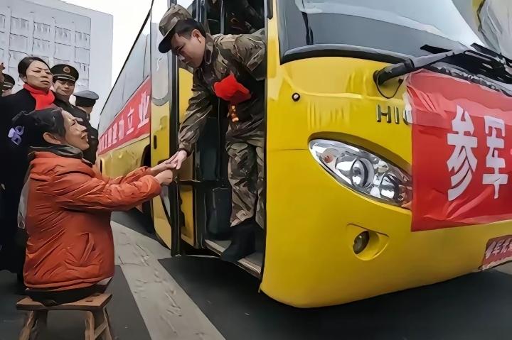 她没有双腿，却用两块小板凳，撑起了送儿从军的路。一步一挪，步履蹒跚，却走得坚定又