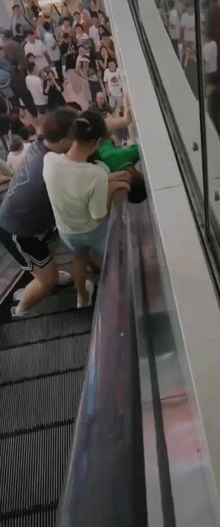 一名小男孩不慎将自己的头夹在了电动扶梯扶手夹缝里！
现场的路人见状马上按了电梯急