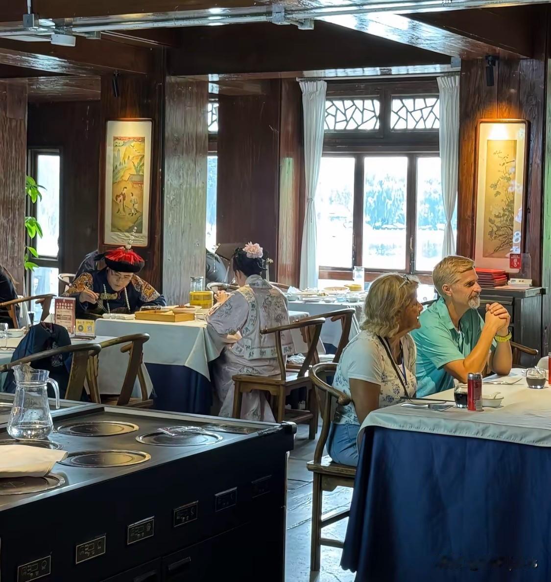 网友拍到一家餐厅里奇妙的画面：穿着清朝王爷、格格衣服的游客正在用膳，旁边是西方游