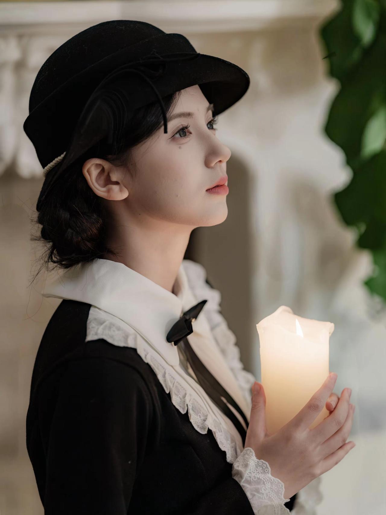 复古法式写真，美妙女子身着黑裙白蕾丝饰边装，戴珍珠饰黑帽，持蜡烛于壁炉前，周围书