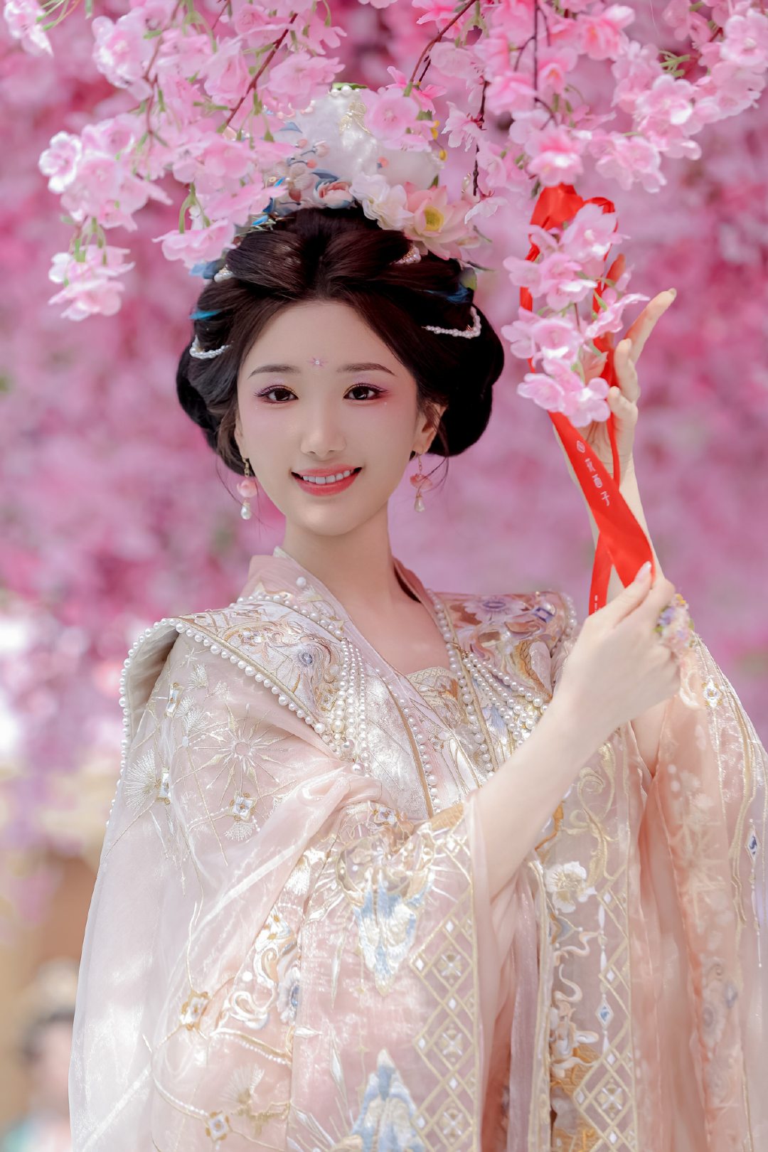 毛晓彤花神妆 春日花朝，毛晓彤站在花树下，发间点缀的鲜花与颊边的薄紫妆色相互映衬