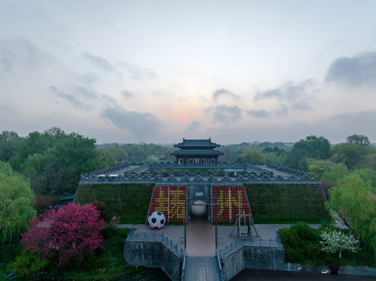 朝阳初升下的扬州宋夹城体育休闲公园，城门旁的扬州字体和足球造型显得特别显眼。