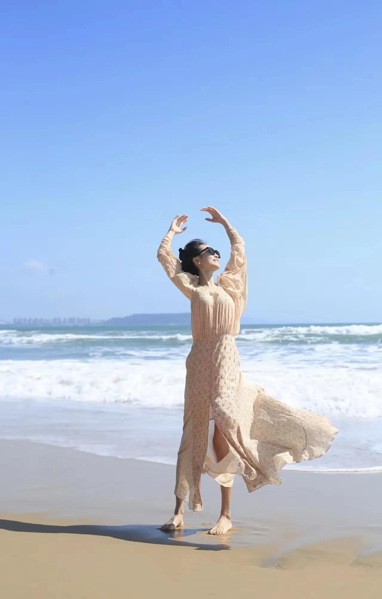珊珊海边漫舞，大海作背景，海风为伴🌊
一袭浅杏长裙，赤脚站在沙滩上，身姿轻盈曼